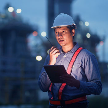 Man with hard hat working with walkie talkie and Ipad