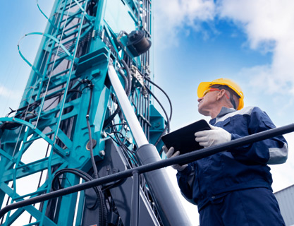 Man with tablet looking up at machinery