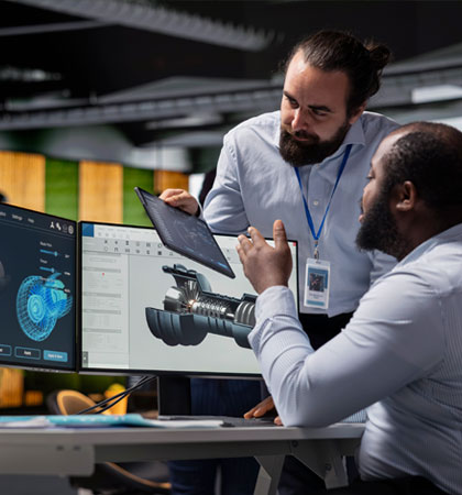 Men collaborating looking at computer and Ipad of machinery parts