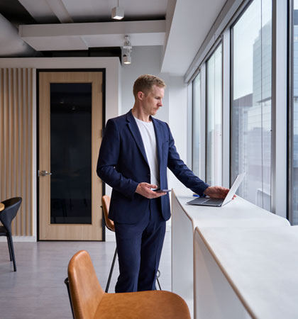 Man standing at window working on computer